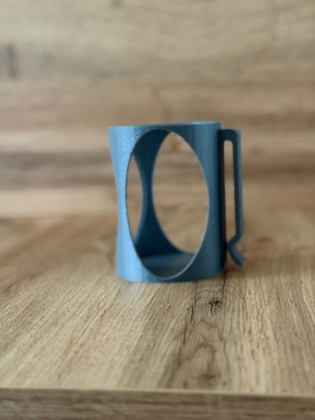 Blauer Becher mit einzigartigem, geschwungenem Design und Haltegriff.