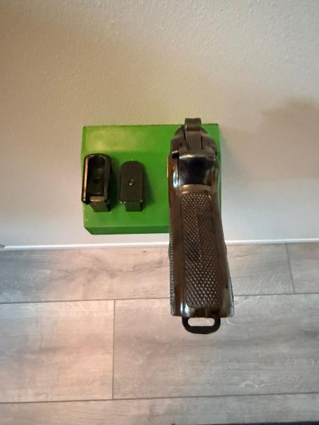 Ein graues Gewehr mit zwei unterstützenden Magazine auf einem grünen Untergrund.