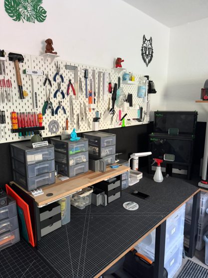 Werkbank mit Werkzeugen und Aufbewahrungsboxen an der Wand, ordentlich organisiert.