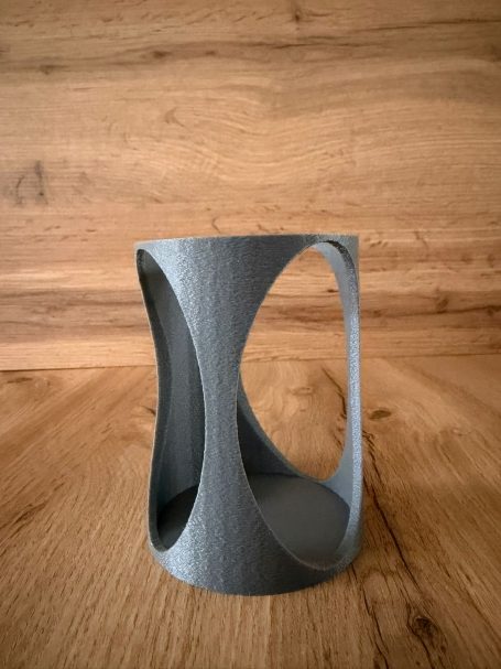 Grauer, geometrischer Behälter mit offenen, geschwungenen Formen.